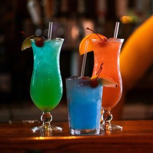 Three colorful drinks are sitting on a bar in Jazz - A Louisiana Kitchen. A New Orleans Bistro Restaurant near me