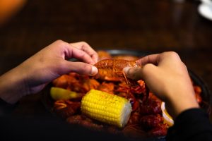 Jazz - A Louisiana Kitchen Hands are peeling a cooked crawfish over a platter with more crawfish, corn on the cob, and lemon slices. Kansas City, Columbia