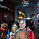 Jazz - A Louisiana Kitchen A group of people taking a selfie on a busy street during a Super Bowl event, with a decorated archway lit up in the background. Kansas City, Columbia, cajun food restaurant near me