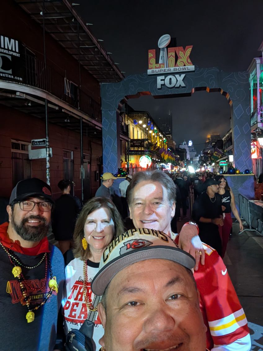 Jazz - A Louisiana Kitchen A group of people taking a selfie on a busy street during a Super Bowl event, with a decorated archway lit up in the background. Kansas City, Columbia, cajun food restaurant near me